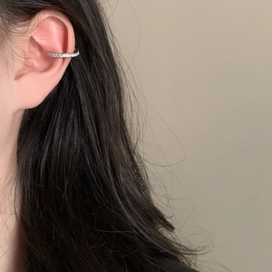 Gros plan d'un ear cuff en argent serti de zircons brillants porté sur le cartilage