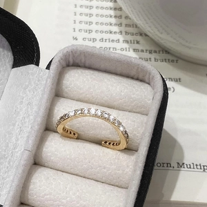 Détail d'une bague ajustable dorée sertie de micro-pavé de zircone sur velours gris