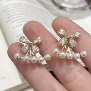 Detailed view of french romantic bow earrings with pavé crystals and pearl accents