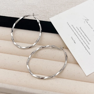 Polished silver twisted hoop earrings with elegant spiral texture on a velvet tray