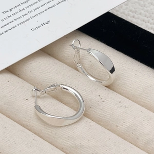 Dettaglio dei cerchi d'argento Mobius twist in un espositore per gioielli in velluto beige