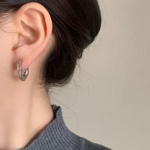 Minimalist U-shaped silver geometric hoop earrings worn by a model in a modern style
