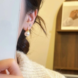 Elegant gold ball fringe pearl earrings with rhinestone stud shown on model in warm light