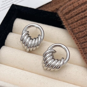 Minimalist silver geometric hoop earrings with textured spiral design on velvet stand