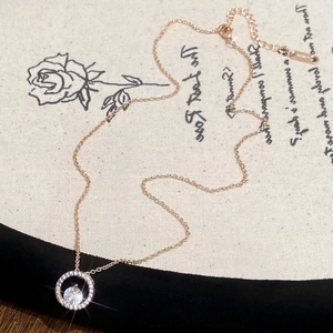 Détail du collier pendentif halo en or rose avec pierres en zircone micro-pavées