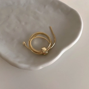 Macro shot of 18K gold snake chain wrap ring with polished square metal buckle and beads