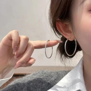 Chic silver starlight textured large hoop earrings worn by a model in minimalist style