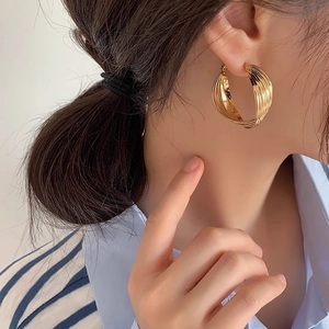 Gros plan de boucles d'oreilles créoles dorées torsadées avec texture en métal multicouche