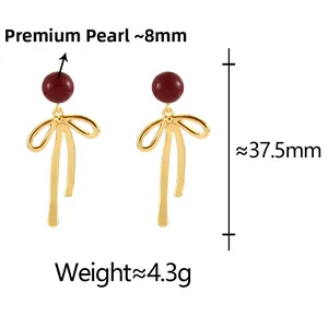 Detail view of gold bow earrings with 8mm red cinnabar pearls showing product dimensions