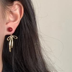 Exquisite gold-plated bow earrings with red cinnabar bead pendant on a model