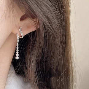 Macro detail of long tassel earrings with sparkling crystals and graduated white pearls