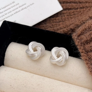 Macro view of matte silver twist stud earrings featuring a geometric spiral design