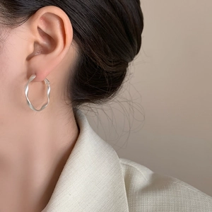 Elegant silver twisted hoop earrings with a matte finish on a female model