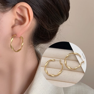 Macro detail of matte gold Mobius twisted hoop earring with secure hinged closure