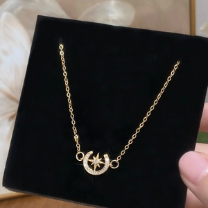 Collier doré avec pendentif étoile et lune serti de zircons sur fond de velours noir