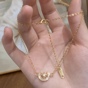 Collier doré avec pendentif étoile et croissant de lune serti de zircons en main