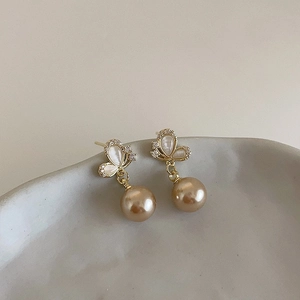 Close-up of butterfly earrings with shell wings and champagne round pearls detail