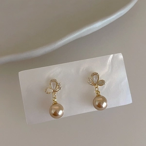 Detail of champagne pearl drop earrings with butterfly design and pavé crystals