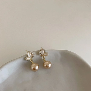 Detail of butterfly stud earrings with opal texture and hanging champagne pearl