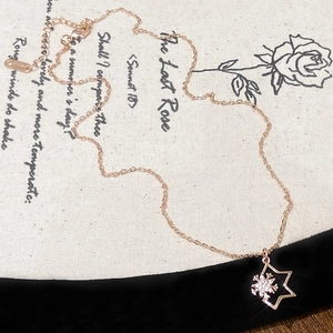 Detail of rose gold star and snowflake pendant necklace with cubic zirconia accents
