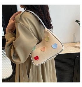 Detail of beige woven shoulder bag with colorful heart patches and silver trim finish