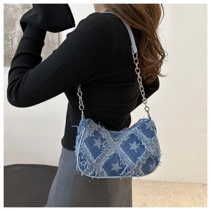 Detail of star-patterned denim hobo bag with frayed edges and silver chain strap