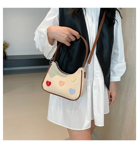 Detail of beige canvas shoulder bag with colorful heart patches and brown leather strap