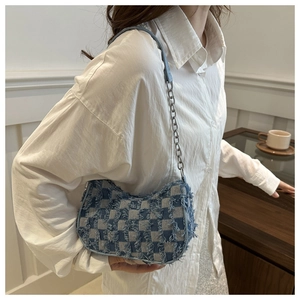 Detail of blue denim checkerboard shoulder bag with frayed edges and silver chain strap