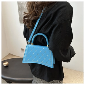 Borsa in pelle trapuntata blu con dettagli di perline e fondo curvo indossata da modella