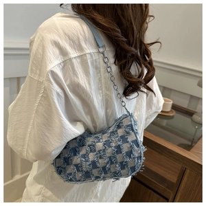 Close-up of denim checkered shoulder bag featuring frayed edges and chain strap detail