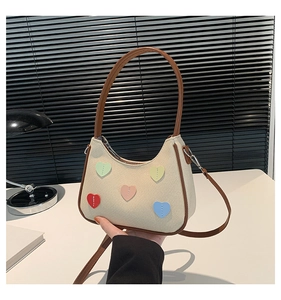 Detail of canvas shoulder bag with multi-colored heart patches and brown PU leather trim