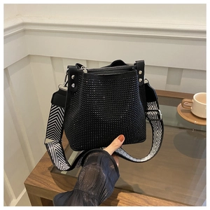 Détail du sac seau en strass noirs avec une large bandoulière en toile à motif zigzag