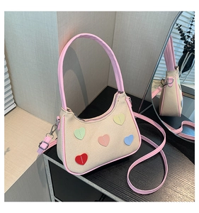 Detail of canvas shoulder bag with colorful heart patches and pink leather handles