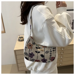 Detail of the vintage floral crescent bag with golden plaque on a model's shoulder