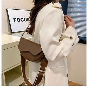 Brown faux leather saddle bag featuring a wide contrast strap and magnetic flap closure