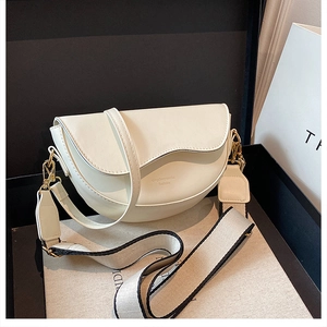 Detail view of cream saddle bag featuring both thin leather and wide jacquard straps