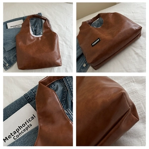 Detail view of brown leather tote bag with fashion label and textured soft surface