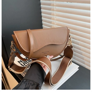 Brown leather saddle bag featuring an asymmetrical flap and a striped wide canvas strap