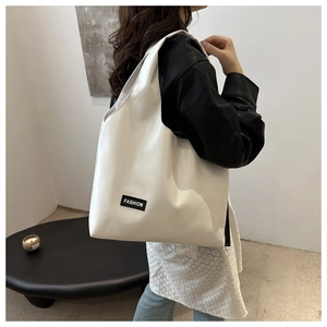 Detail of white PU leather tote bag with Fashion label shown on model shoulder