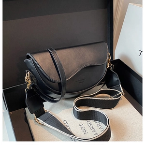Detail of a black saddle bag with wavy flap, dual straps and premium gift box packaging