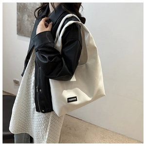 Close-up of a large beige PU leather tote bag with a minimalist Fashion label for women