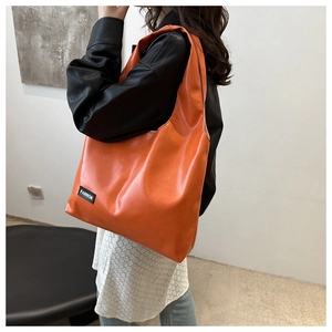 Detailed macro view of the bright orange PU leather tote bag with fashion label