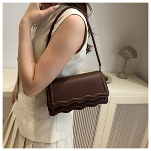 Detail of dark brown leather handbag with unique triple-layered wave-edge design