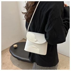 Close-up of a white patent leather bucket bag with FASHION & BAGS print and round buckle
