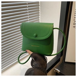 Close-up of green leather mini bucket bag with gold fashion lettering and magnetic closure