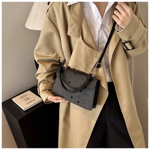 Dunkelgraue Ledertasche mit schwarzen Sternen als Umhängetasche zum Trenchcoat getragen