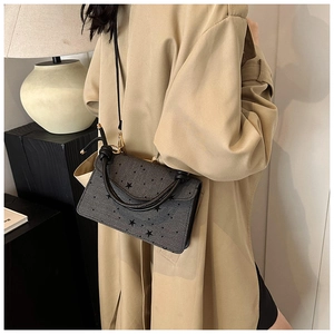 Detail der dunkelgrauen Handtasche mit schwarzen Sternen und ledernem Schultergurt