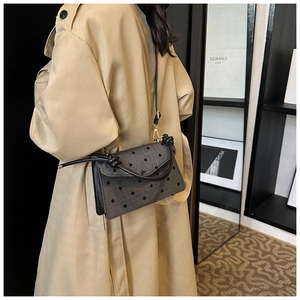Chic grey polka dot crossbody bag detail featuring elegant fabric texture and black leather strap