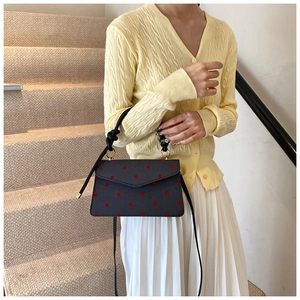 Polka dot crossbody bag featuring a knotted handle and vibrant red dots on navy fabric