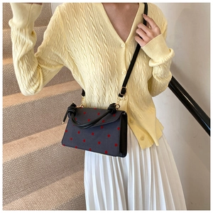 Polka dot crossbody bag with red spots and knotted handle shown in lifestyle context